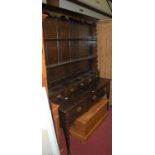 A 19th century oak dresser, having wavy cut frieze over twin plate racks to five short drawers, over