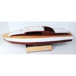 A kit built wooden and balsa wood model of a radio controlled cabin cruiser finished in maroon and