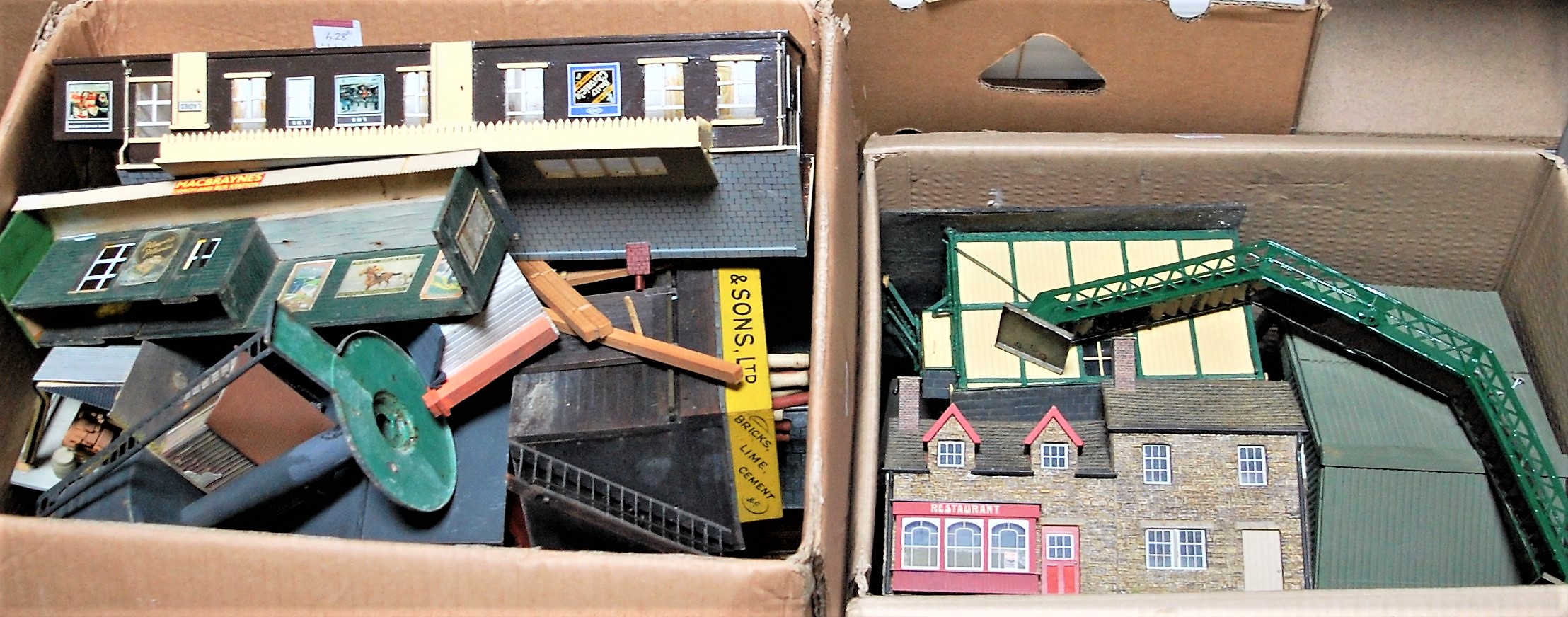 Two large boxes containing buildings as removed from layout - including station, footbridge,