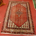 A Persian woollen red ground rug, 200x125cm