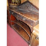 A late 19th century heavily carved oak ledgeback buffet whatnot, having twin frieze drawers over