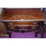 A reproduction hardwood four drawer lowboy, raised on floral carved cabriole supports in the