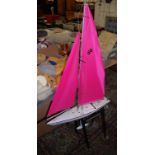 A radio controlled model of a Sea Dolphin pond yacht, fitted with pink nylette sailsCondition