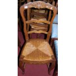 A set of six early 20th century provincial French oak ladder back rush seat dining chairs