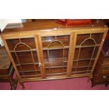 A 1930s walnut and figured walnut three door glazed bookcase, raised on cabriole supports, width