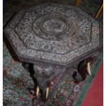 A circa 1900 Indian heavily carved hardwood octagonal occasional table, raised on elephant trunk