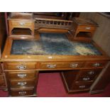 A late Victorian oak and rexine inset twin pedestal writing desk, having a raised superstructure