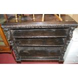 A circa 1900 heavily carved and ebonised oak freestanding open bookshelf, having masked and floral