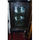 An antique floral relief carved oak single astragal glazed corner cabinet on stand, height 168cm