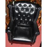 A contemporary black button back vinyl and further studded wingback scroll armchair, having a