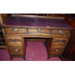 An early 20th century oak and burgundy rexine inset kneehole writing desk, having three frieze