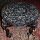 A circa 1900 Indian heavily carved hardwood circular occasional table, raised on elephant trunk