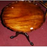 A Georgian style mahogany piecrust tilt-top pedestal tripod table, raised on hipped supports to claw