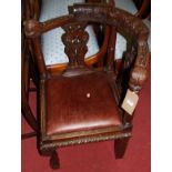 A circa 1900 heavily carved oak tub corner elbow chair, having tan leather drop-in pad seat with