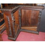 A late 19th century heavily carved oak freestanding open corner bookshelf, the columns carved with