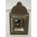 A 20th century brass cushion mirror with leaf scroll and floral decoration and central cupboard door