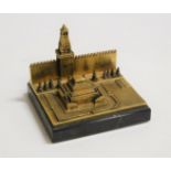 A modern brass desk weight in the form of a Russian building with Cyrillic script on a black