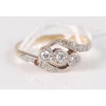 An 18ct and platinum crossover style three stone diamond ring, with three single cut diamonds set in