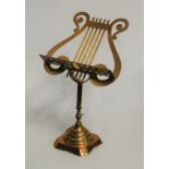 An early 20th century brass adjustable lectern, of lyre shape, having floral embossed decoration,