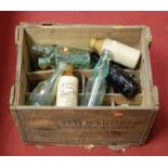 A wooden crate containing various stoneware and glass bottles to include W Everett of Cromer