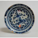 A 19th century Delft blue and white plate, typically decorated with various flowers within scrolling