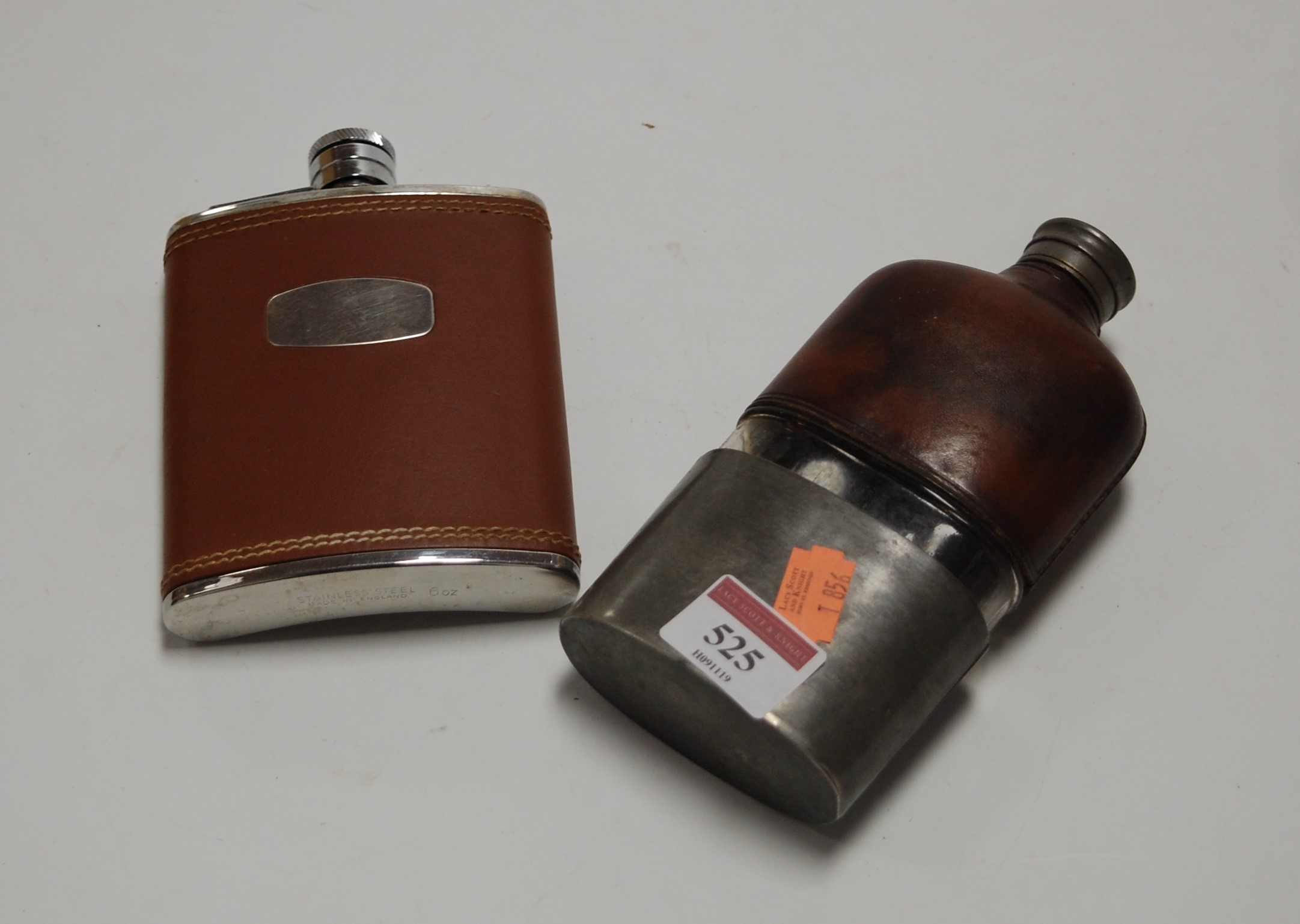 An early 20th century hip flask having leather clad glass body with removable pewter cup, together