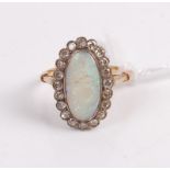 An early 20th century yellow metal opal and diamond set dress ring, the cabochon opal (cracked)