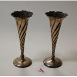 A pair of late Victorian silver trumpet shaped spill vases, each of wrythen form, on loaded bases,