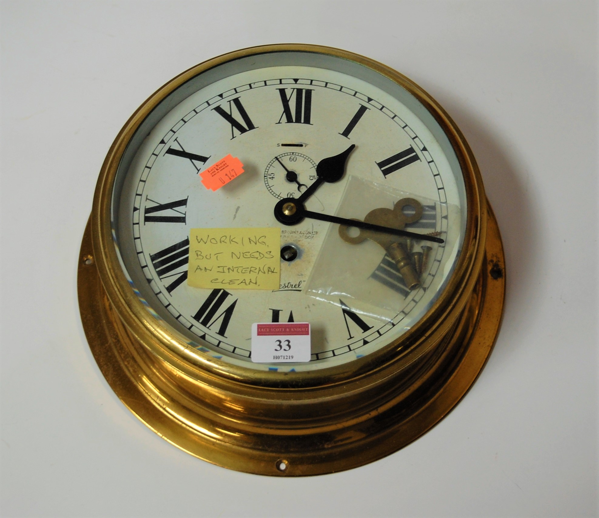 A Sestrel brass cased ships bulkhead clock having a circular enamel dial with Arabic numerals and