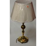 A large turned brass table lamp having a pleated silk shade, height 70cm