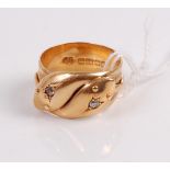 An 18ct gold snake ring modelled as two entwined snakes, each head set with a small rose cut