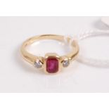 A 18ct gold ruby and diamond ring, the centre emerald cut ruby measuring approx 5.5x3.75mm,