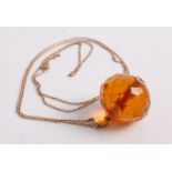 A faceted clear orange amber ball pendant, of good size, on 9ct gold finelink neck chain, pendant