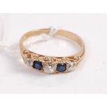 A yellow metal sapphire and diamond dress ring, arranged as three old round cut diamonds,