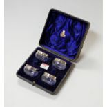 A set of four Victorian glass open salts each having a silver collar in fitted black leather case