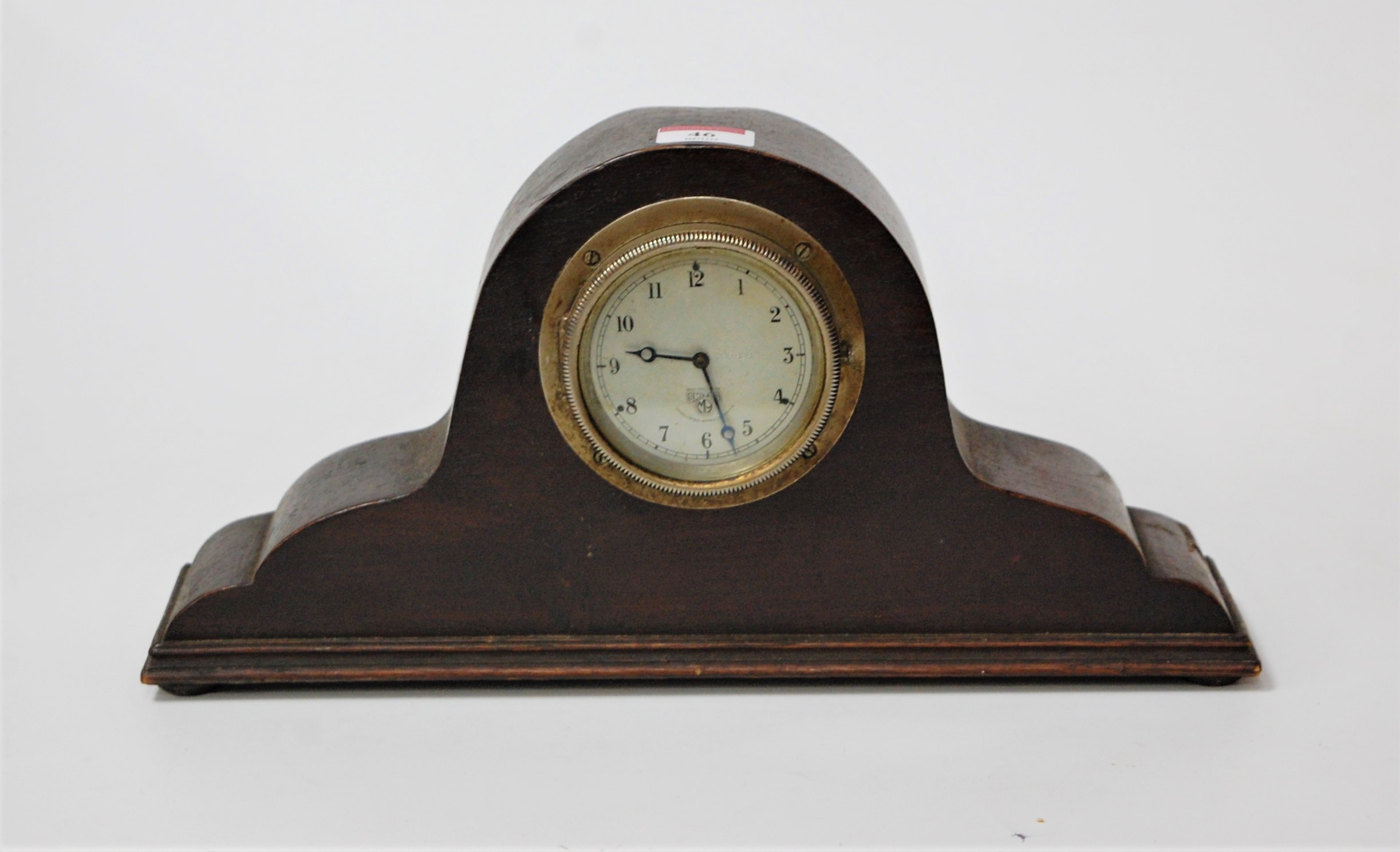 A 1950s oak cased mantel clock having a silvered dial with Arabic numerals