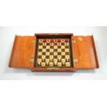 A circa 1900 mahogany folding travel chess set, having natural and stained carved bone pieces