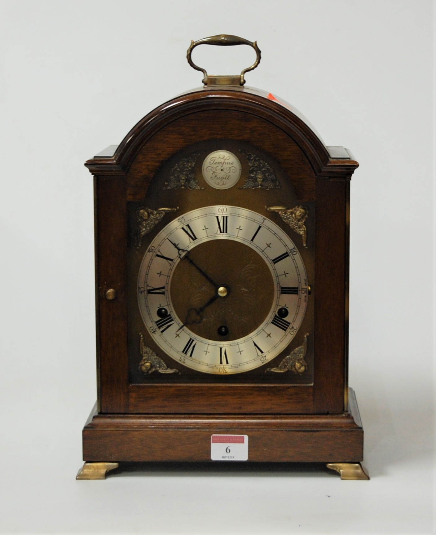 A modern mahogany cased bracket clock having an arched brass dial with silvered chapter ring,