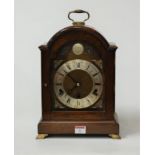 A modern mahogany cased bracket clock having an arched brass dial with silvered chapter ring,
