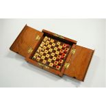 A circa 1900 mahogany cased folding travel chess set, having natural carved and stained bone chess