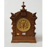 A late 19th century American oak cased mantel clock, the brass dial with Arabic numerals having an
