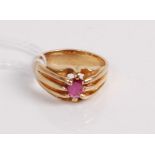 A yellow metal ruby set ring, the round cut ruby in an eight claw setting with reeded shoulders,
