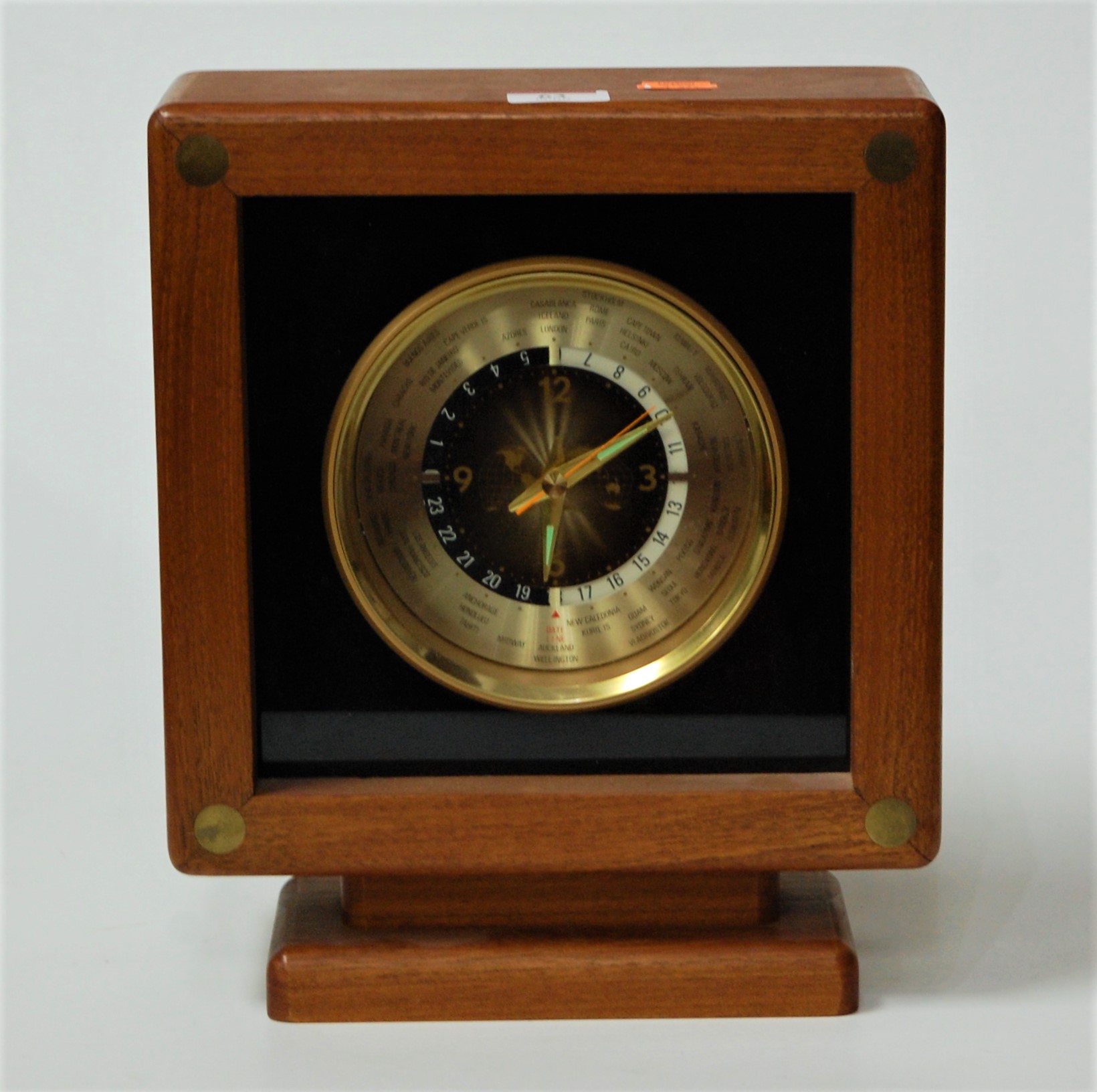 A modern teak cased World Time Clock with revolving dial showing various countries, height 29cm