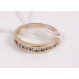 A yellow metal diamond set half eternity ring arranged as 11 channel set small brilliants, stamped