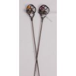 A pair of white metal hat-pins, each set with thistle, one with amethyst and the other with orange