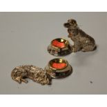 A matched pair of white metal open salts, each in the form of a retriever with bowl at his feet,