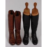 A pair of mid-20th century black leather calf length riding boots, with wooden trees, together