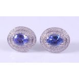 A pair of white metal, tanzanite and diamond oval cluster earrings, each featuring a centre oval