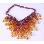 A multi-strand amber fringe necklace, comprising varying shades of amber pieces with a barrel clasp,