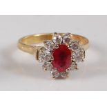 A yellow and white metal, ruby and diamond oval cluster ring, featuring a centre oval faceted ruby